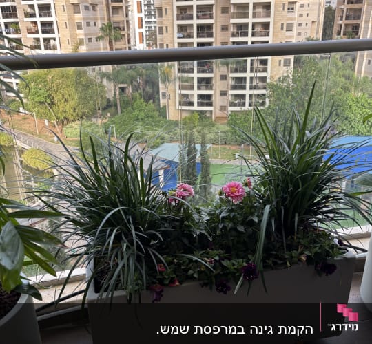 עציץ עם פרחים ודשא מלאכותי במרפסת